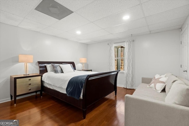 bedroom with a drop ceiling and dark hardwood / wood-style floors