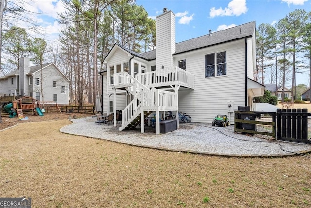 rear view of house featuring a playground, a patio, a wooden deck, and a lawn