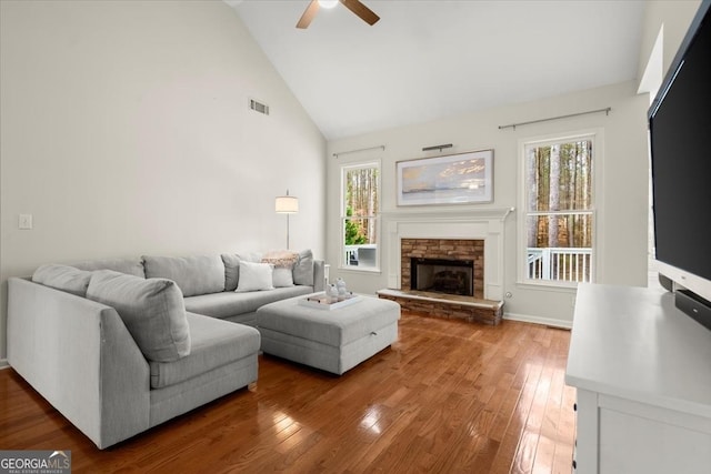 living room with a fireplace, wood-type flooring, high vaulted ceiling, and ceiling fan