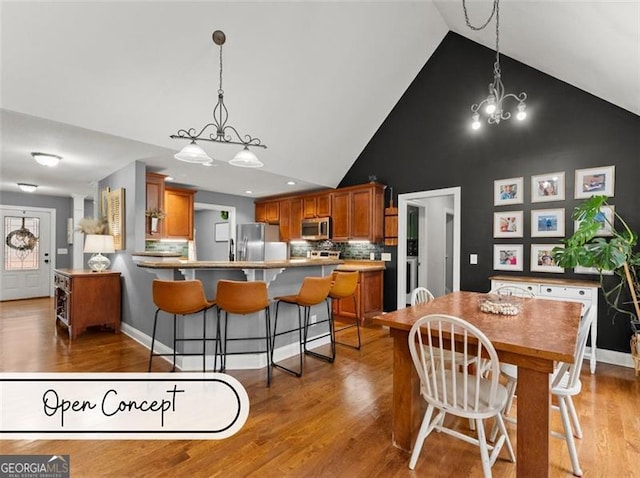 dining room featuring wood-type flooring, an inviting chandelier, and high vaulted ceiling