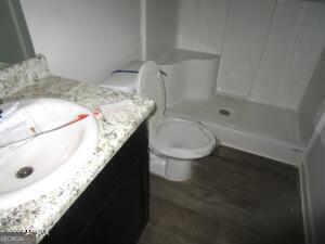 bathroom featuring walk in shower, vanity, toilet, and wood-type flooring