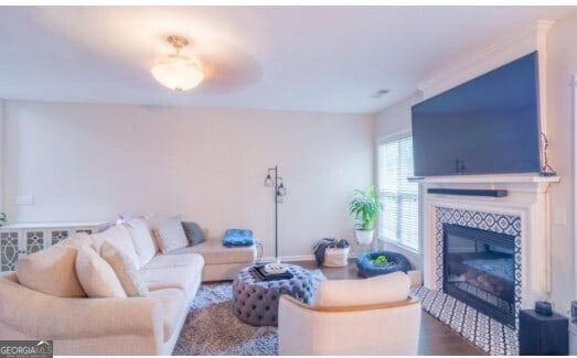 living room featuring wood-type flooring and a tiled fireplace