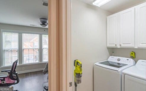 clothes washing area with ceiling fan, cabinets, and washing machine and dryer