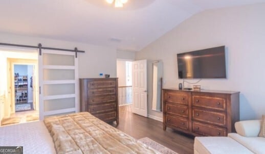 bedroom featuring a barn door, lofted ceiling, and dark hardwood / wood-style flooring