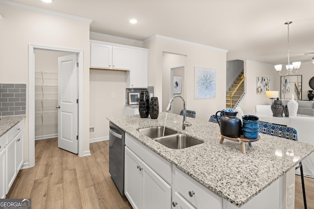 kitchen featuring sink, dishwasher, white cabinets, a center island with sink, and decorative light fixtures