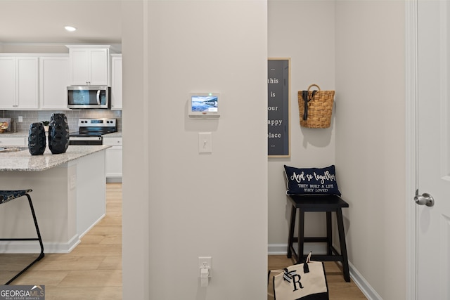 kitchen with appliances with stainless steel finishes, backsplash, white cabinets, and light stone counters