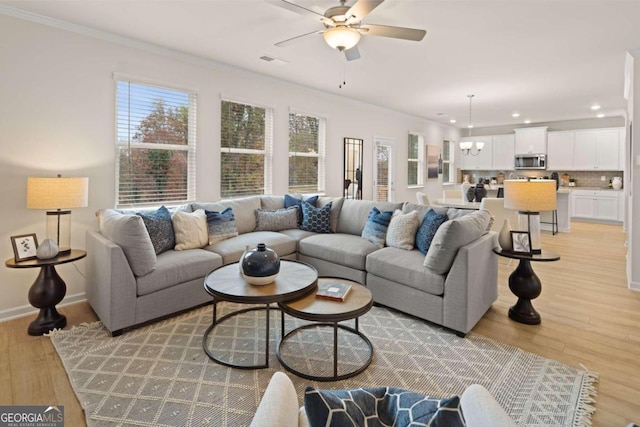 living room featuring crown molding, light hardwood / wood-style flooring, and ceiling fan with notable chandelier