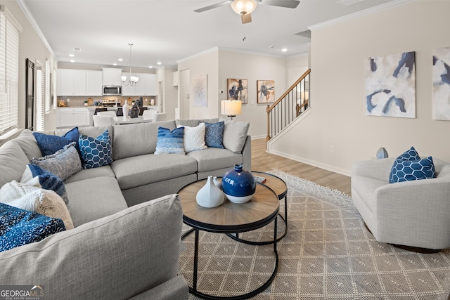 living room with ornamental molding, dark hardwood / wood-style floors, and ceiling fan with notable chandelier