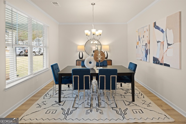 dining area with an inviting chandelier, crown molding, and light hardwood / wood-style flooring