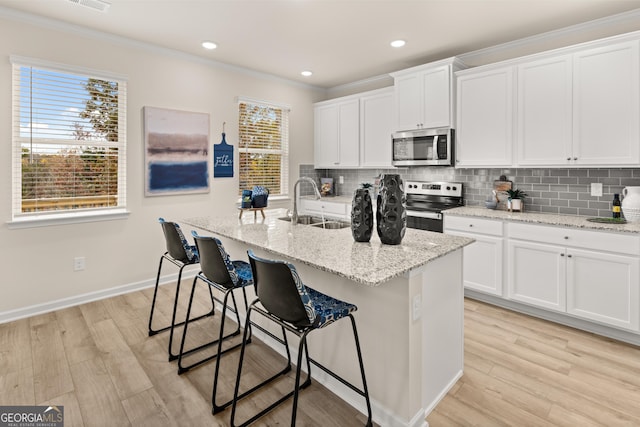 kitchen featuring white cabinetry, appliances with stainless steel finishes, sink, and an island with sink