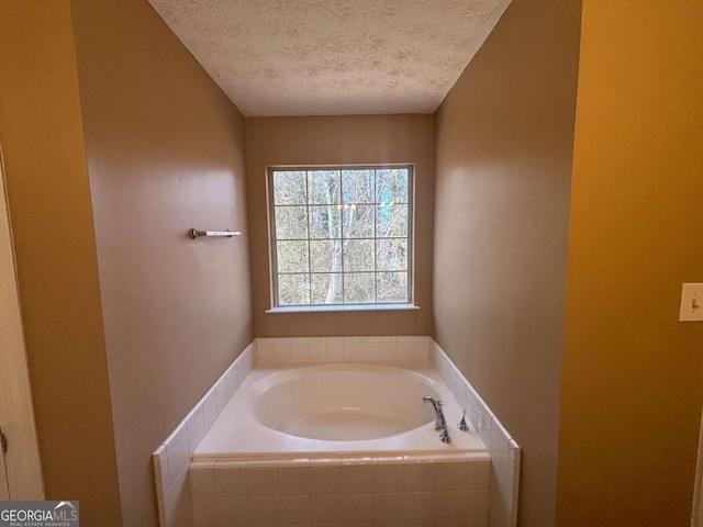 bathroom with a relaxing tiled tub and a textured ceiling