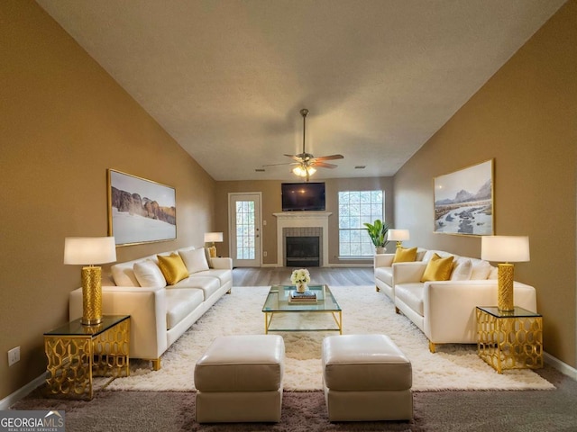 living room with a tile fireplace, lofted ceiling, and ceiling fan