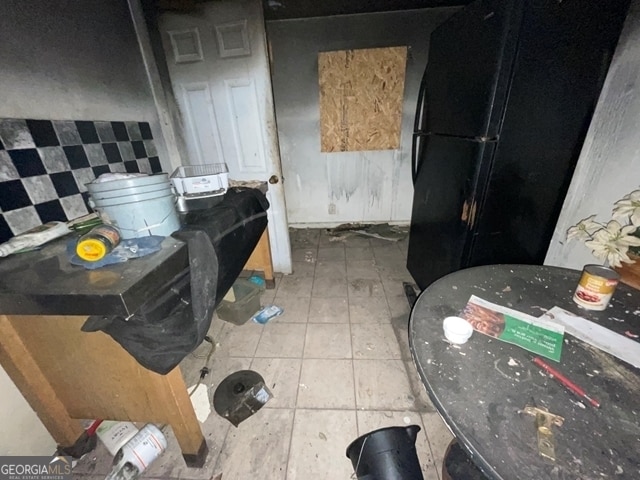 kitchen featuring tile patterned flooring, backsplash, and black fridge