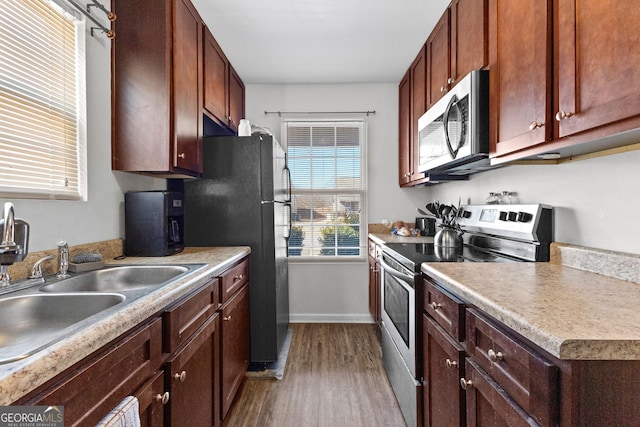 kitchen featuring stainless steel appliances, sink, and light hardwood / wood-style floors