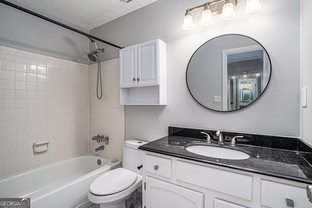 full bathroom featuring vanity, a textured ceiling, toilet, and tiled shower / bath