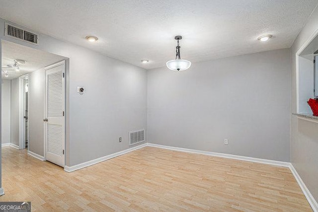 unfurnished room with a textured ceiling and light wood-type flooring