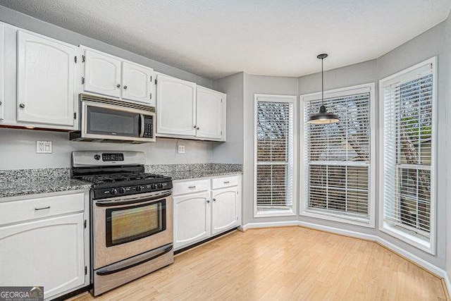 kitchen with white cabinetry, stainless steel appliances, light hardwood / wood-style flooring, and pendant lighting