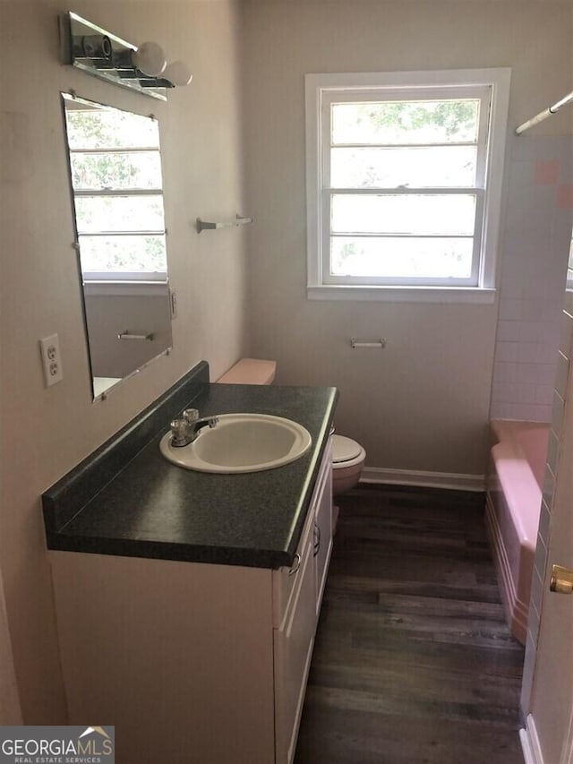 bathroom with hardwood / wood-style flooring, a healthy amount of sunlight, vanity, and toilet