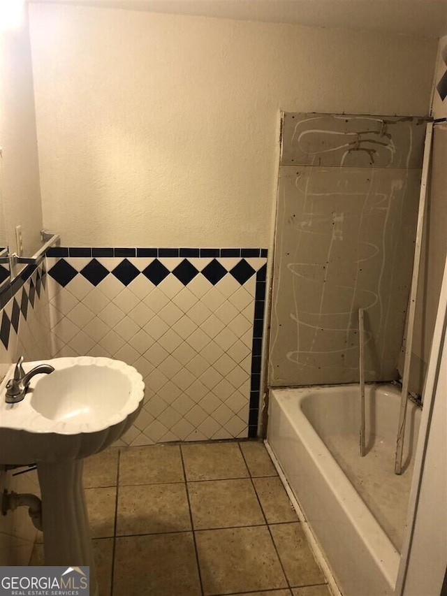 bathroom featuring tile patterned flooring, sink, a bathtub, and tile walls