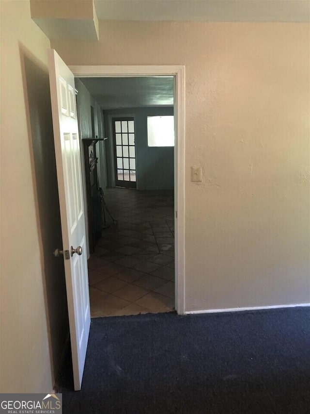 hall featuring dark colored carpet