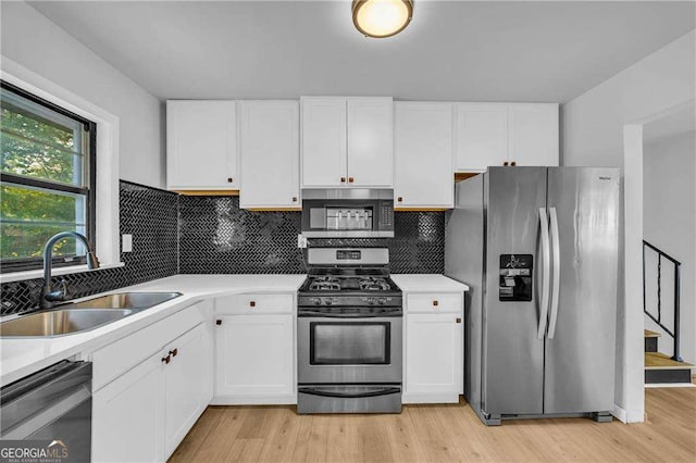 kitchen with backsplash, appliances with stainless steel finishes, sink, and white cabinets