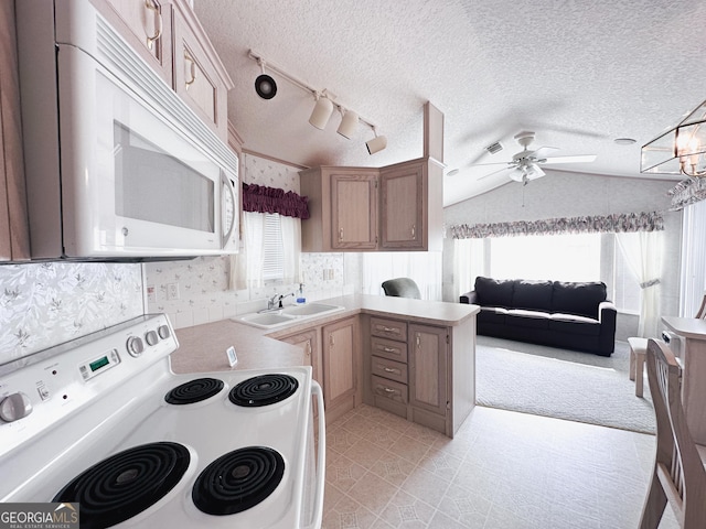 kitchen with white appliances, plenty of natural light, sink, and vaulted ceiling