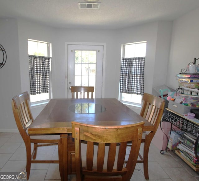 dining space featuring a healthy amount of sunlight, light tile patterned floors, and a textured ceiling