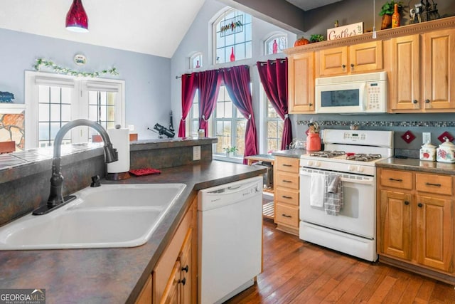 kitchen featuring lofted ceiling, sink, white appliances, and hardwood / wood-style floors