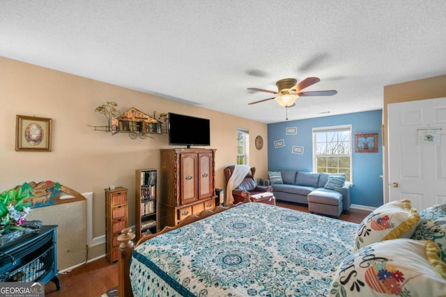 bedroom featuring dark hardwood / wood-style flooring, ceiling fan, and a textured ceiling