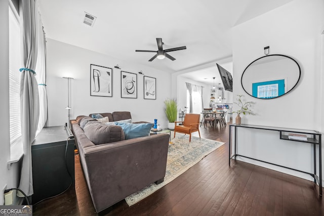 living room featuring dark wood-type flooring and ceiling fan