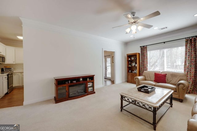 carpeted living room featuring crown molding and ceiling fan