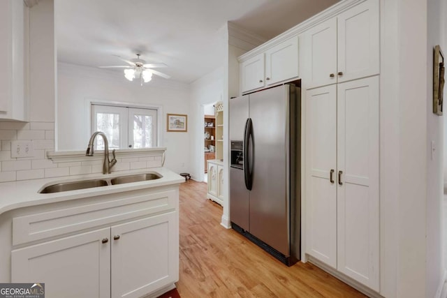 kitchen with sink, light hardwood / wood-style flooring, stainless steel fridge, backsplash, and white cabinets