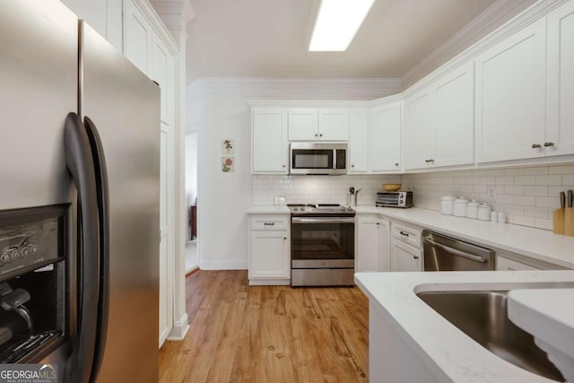 kitchen with sink, white cabinets, backsplash, stainless steel appliances, and light wood-type flooring