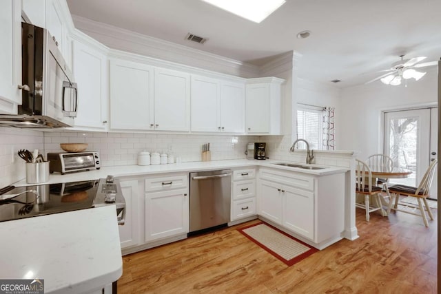 kitchen featuring white cabinetry, appliances with stainless steel finishes, decorative backsplash, and light wood-type flooring