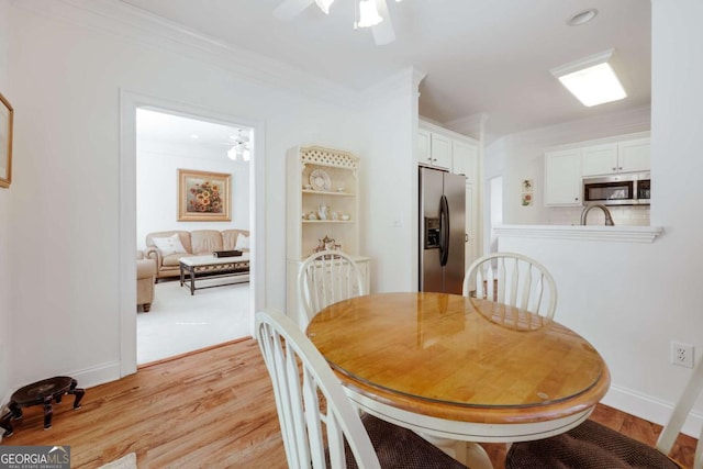 dining area with crown molding, ceiling fan, and light hardwood / wood-style floors