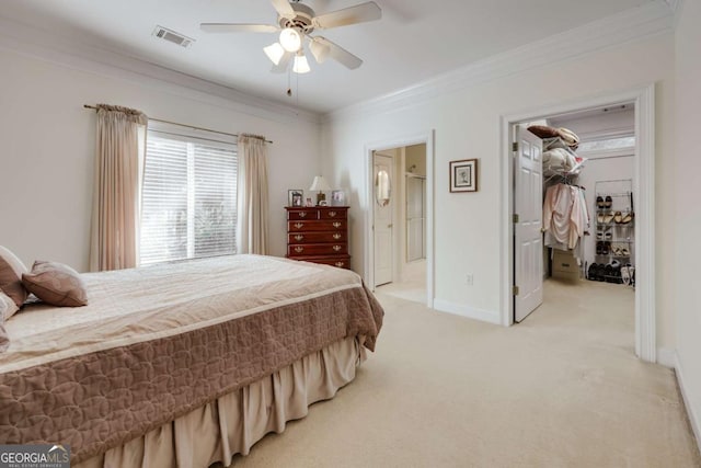 carpeted bedroom with ceiling fan, ornamental molding, a spacious closet, and ensuite bathroom