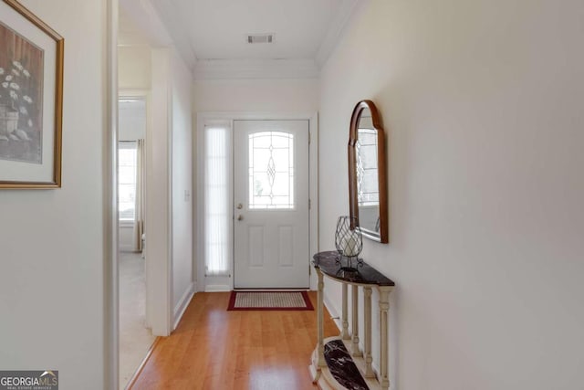 foyer with ornamental molding and light hardwood / wood-style floors