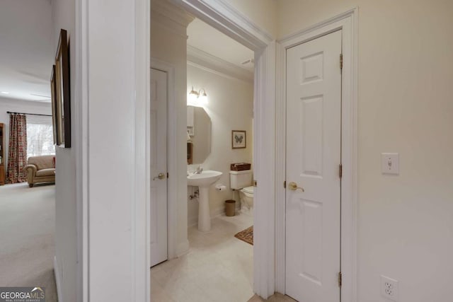 hallway featuring ornamental molding and light colored carpet