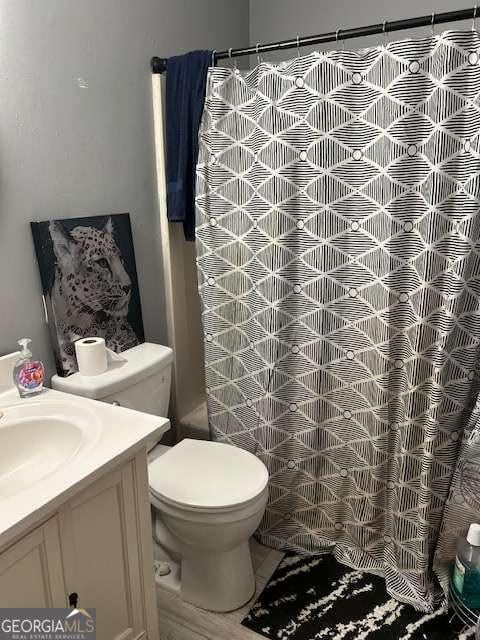 bathroom with walk in shower, vanity, and toilet