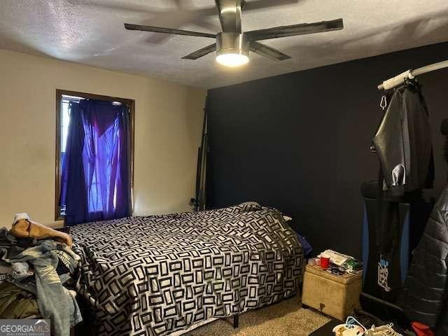 carpeted bedroom featuring ceiling fan and a textured ceiling