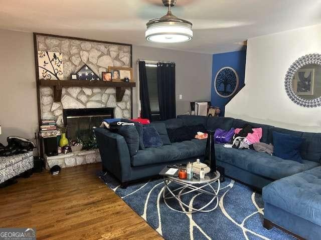 living room featuring wood-type flooring and a stone fireplace