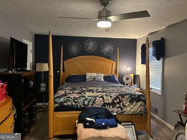 bedroom with ceiling fan, a textured ceiling, and dark colored carpet