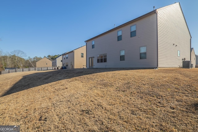 back of property with central AC and a lawn