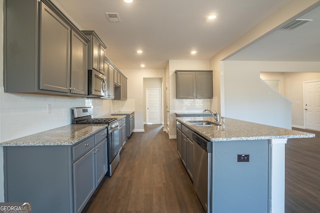 kitchen with an island with sink, stainless steel appliances, dark hardwood / wood-style flooring, and sink