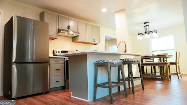 kitchen featuring sink, gray cabinetry, stainless steel fridge, a kitchen bar, and dark wood-type flooring