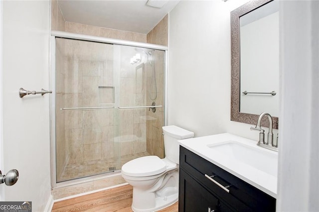 bathroom featuring walk in shower, hardwood / wood-style floors, vanity, and toilet