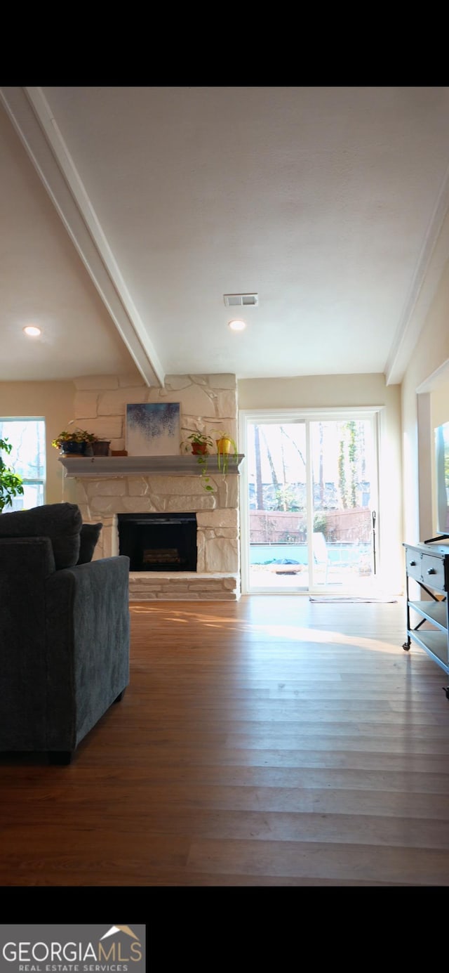 living room featuring beam ceiling, hardwood / wood-style flooring, a fireplace, and a healthy amount of sunlight