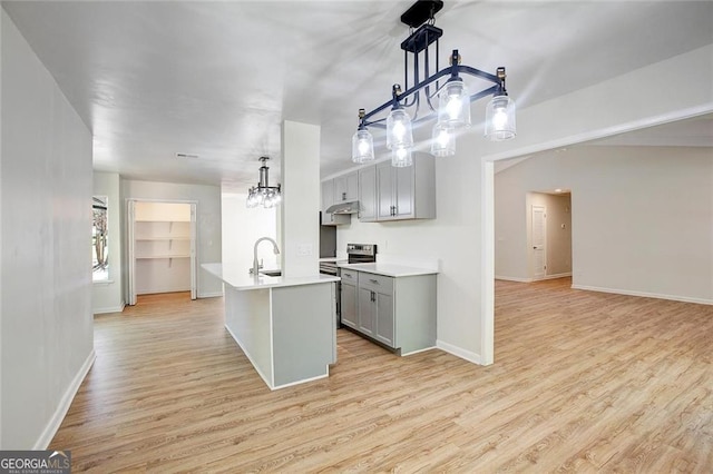 kitchen with a kitchen island with sink, sink, decorative light fixtures, and stainless steel electric range oven