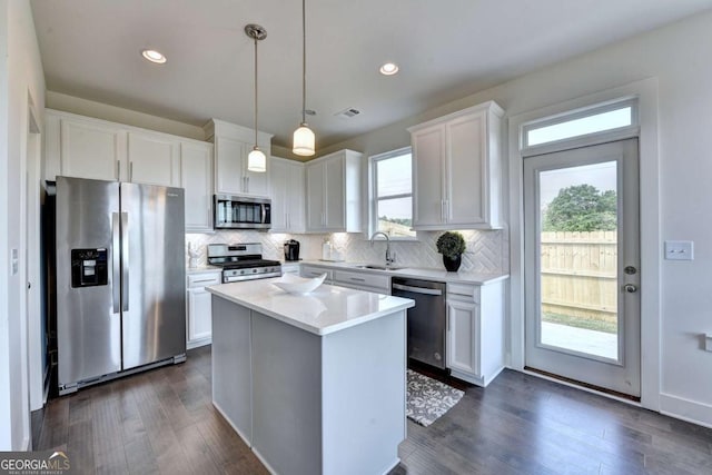 kitchen with decorative light fixtures, tasteful backsplash, white cabinetry, a center island, and stainless steel appliances