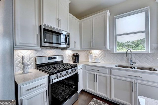 kitchen featuring sink, white cabinetry, appliances with stainless steel finishes, light stone countertops, and decorative backsplash